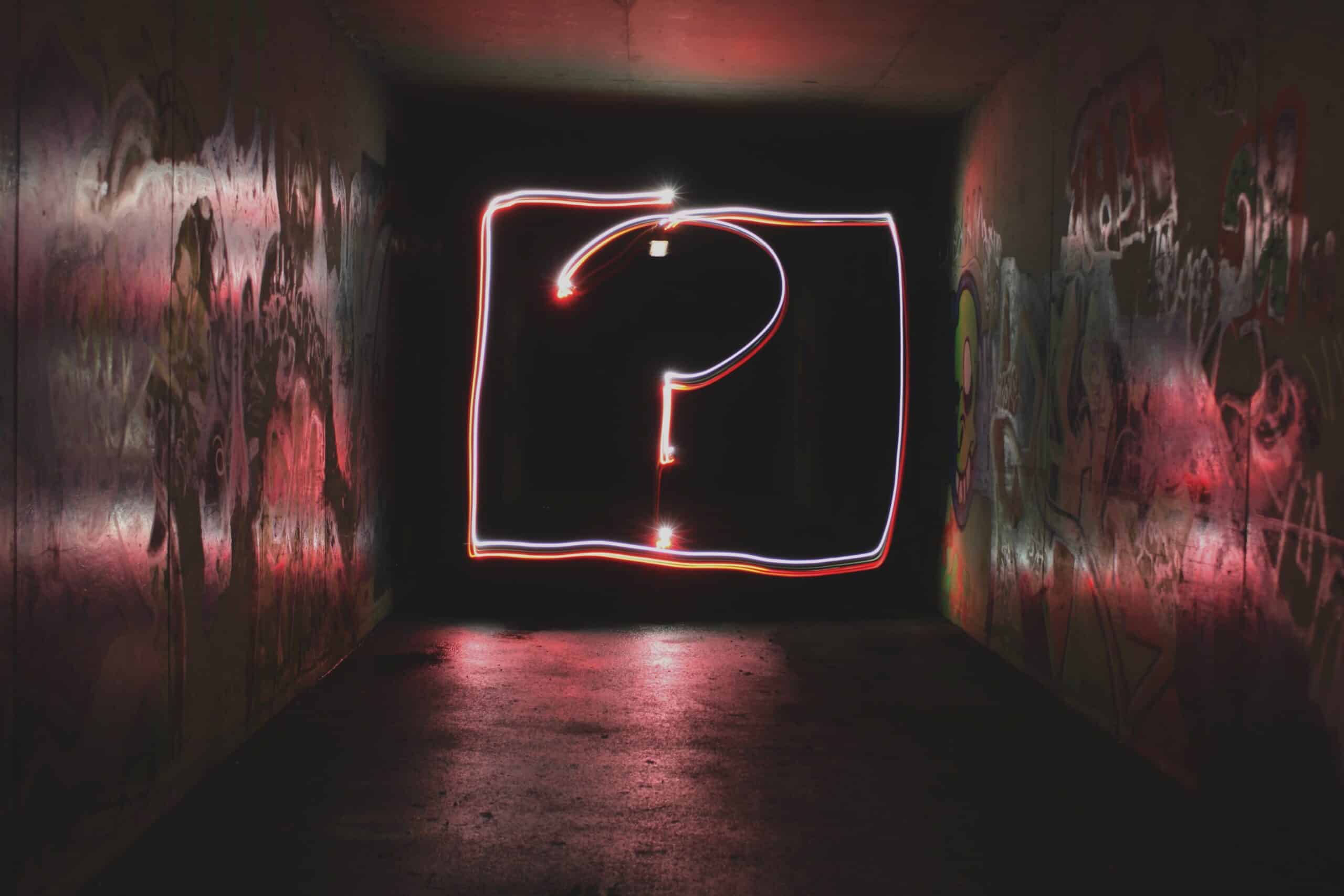 a dark hallway with a question mark on the wall that is glowing red