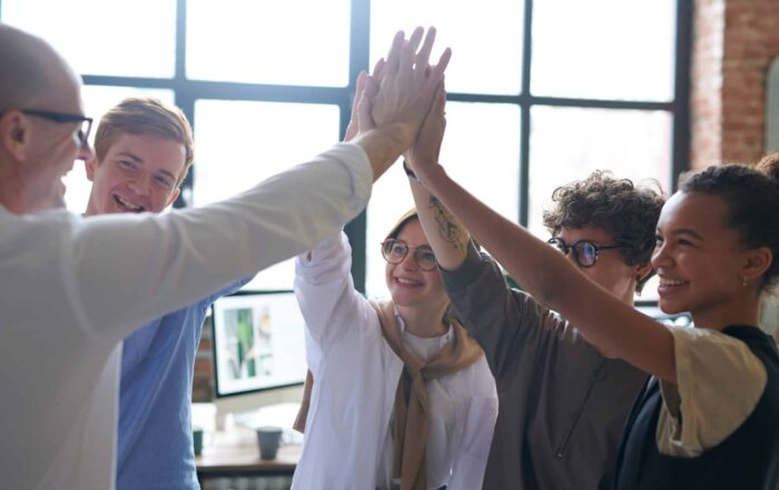 A group of five co-workers high fiving each other