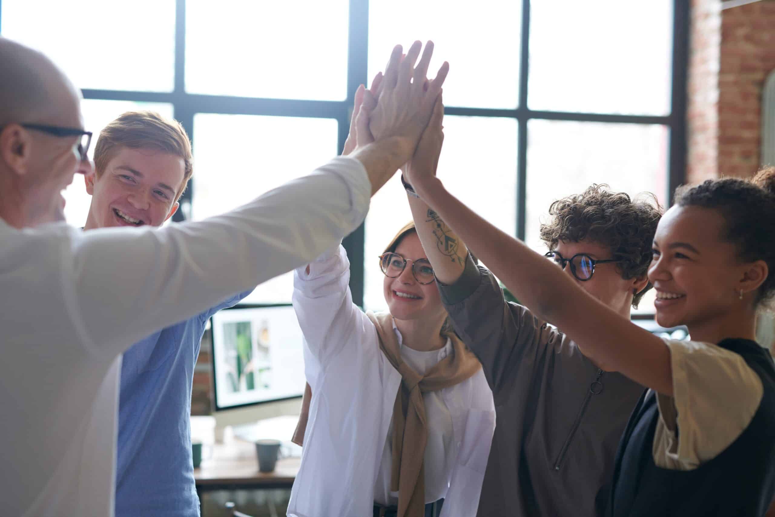 A group of five co-workers high fiving each other