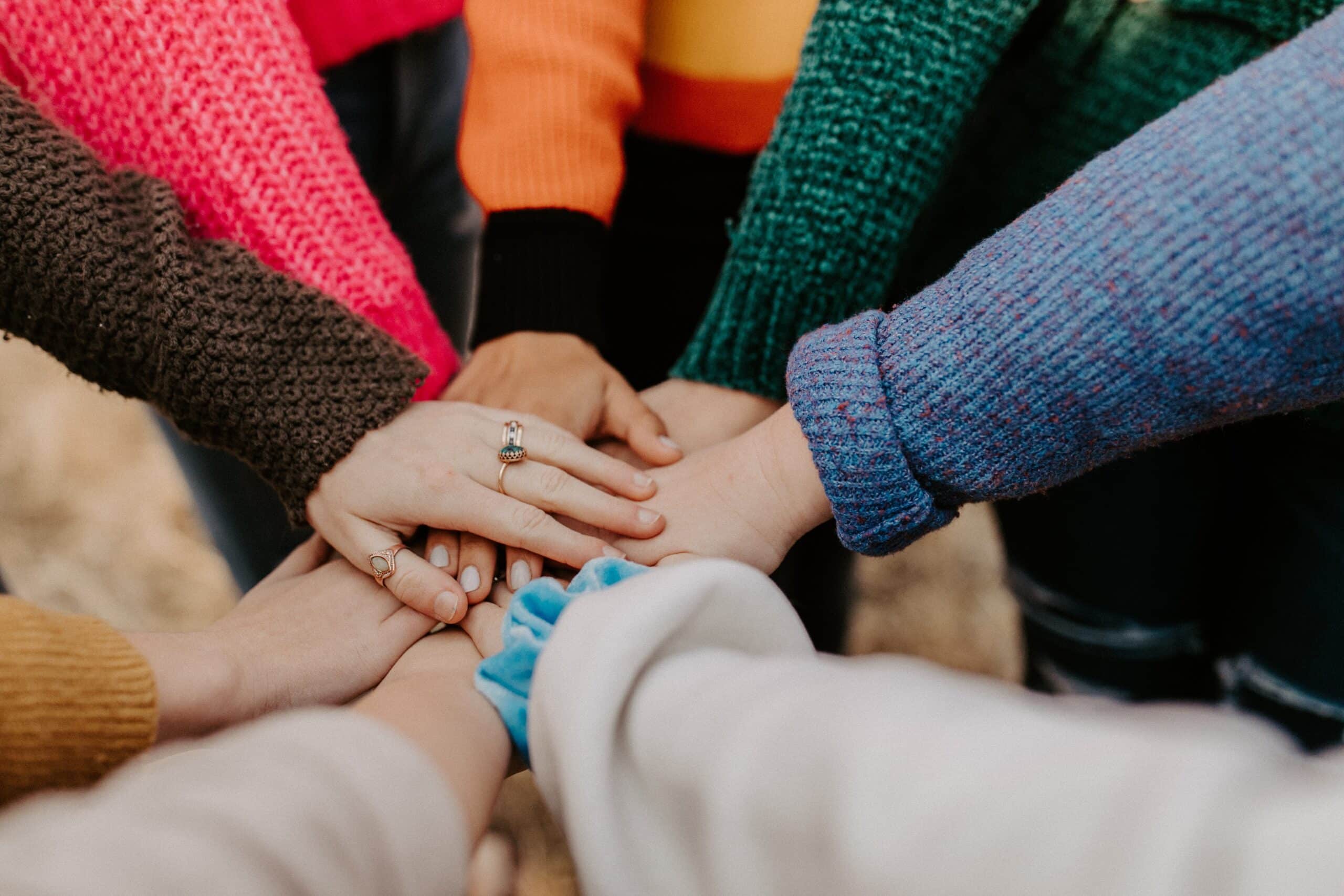 A group of individuals putting there hands together in a pile.